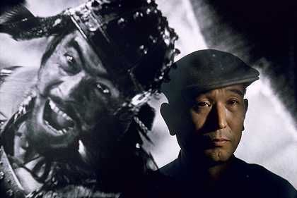 电影导演黑泽明（Akira Kurosawa）站在他的主要明星三村俊郎（Toshiro Mifune）的照片前，日本东京（1963年） by Brian Brake